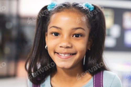 Preview: In school, young African American girl wearing a backpack standing