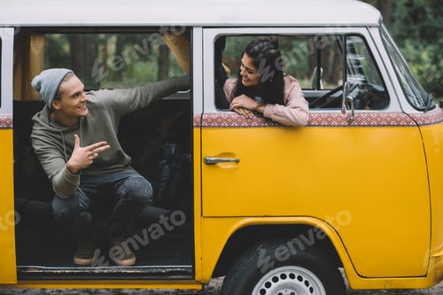 Preview: young happy couple talking while sitting in retro styled minivan