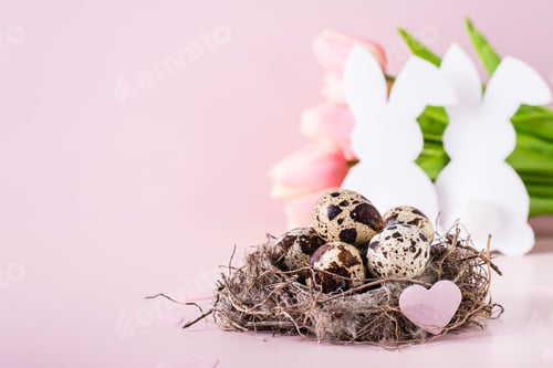 Preview: Happy easter white rabbits near the nest with quail eggs on a pink background.