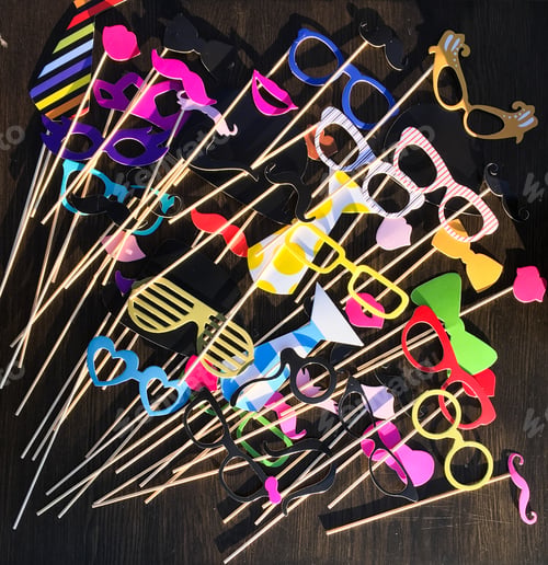 Preview: Lot of paper glasses and mustaches for a party on a wooden surface