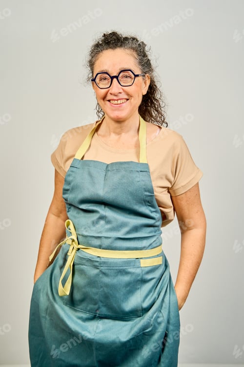 Preview: A woman wearing a blue apron with yellow trim is smiling