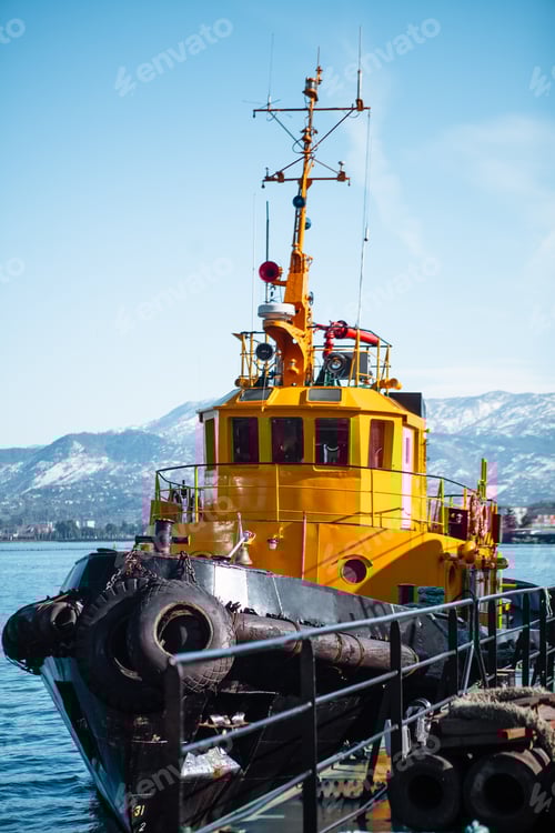 Preview: bright yellow boat in the seaport against the backdrop of mountains