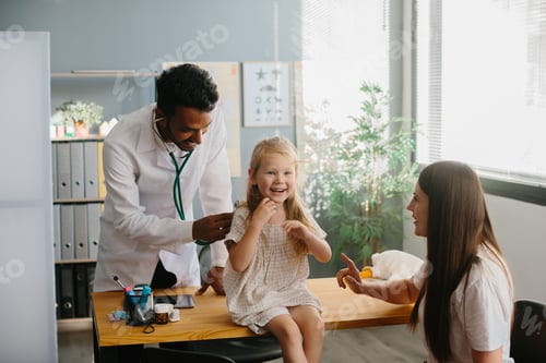 Preview: Smiling pediatrician with stethoscope checking little girl's lungs.