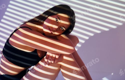Preview: Sitting on the floor. Beautiful young woman is in projector neon lights in the studio