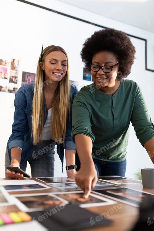 Preview: Diverse female business colleagues brainstorming holding smartphone in meeting room