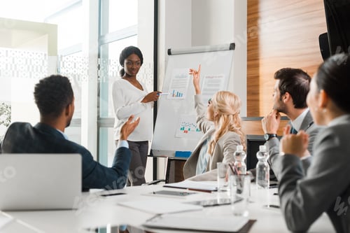 Preview: young multicultural businesspeople looking at african american colleague standing near flipchart