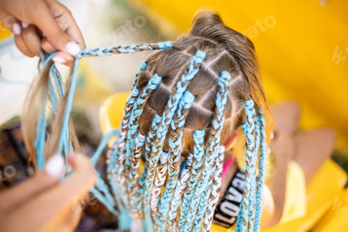 Preview: A girl in a suit weaves African braids in her hair on a sunny day