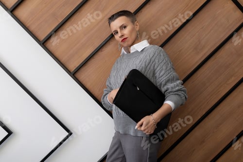 Preview: portrait of a business woman with a folder for documents on the background of the office wall