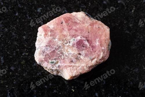 Preview: sample of rough pink ruby mineral on black granite