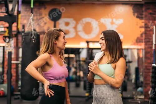 Preview: two young women talking in the gym while resting