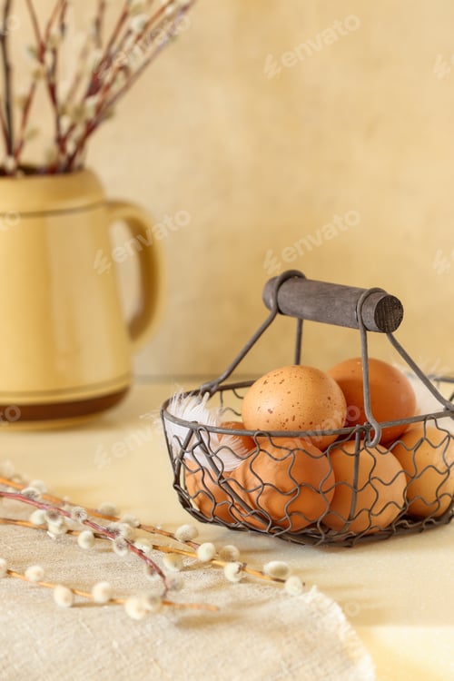 Preview: On a light table there is a vintage basket with Easter eggs, decorated with feathers