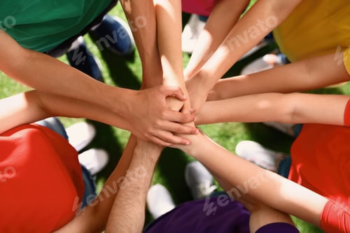 Preview: Group of volunteers joining hands together outdoors, top view