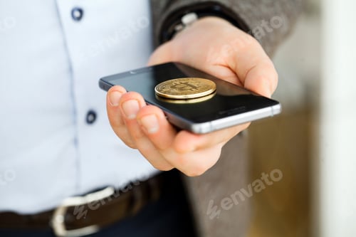 Preview: Hand holding smart phone with bitcoin concept on screen.