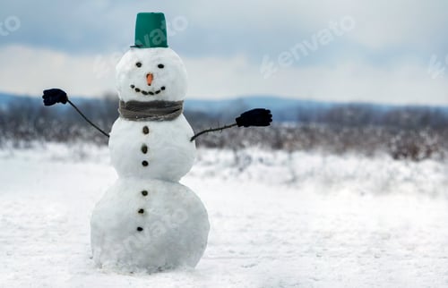 Preview: Big smiling snowman with bucket hat, scarf and gloves on white snowy field winter landscape, blurred