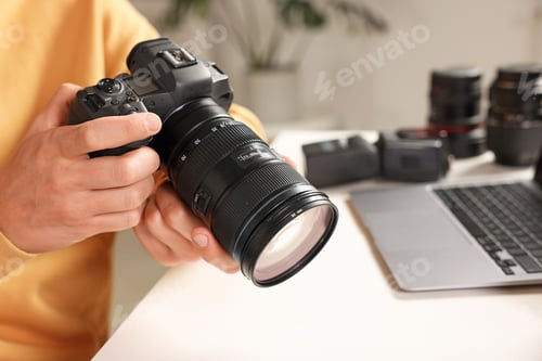 Preview: Photographer with professional camera at white desk indoors, closeup