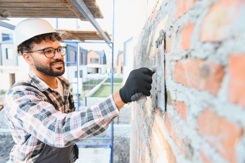 Preview: Construction worker plastering brick wall during house building