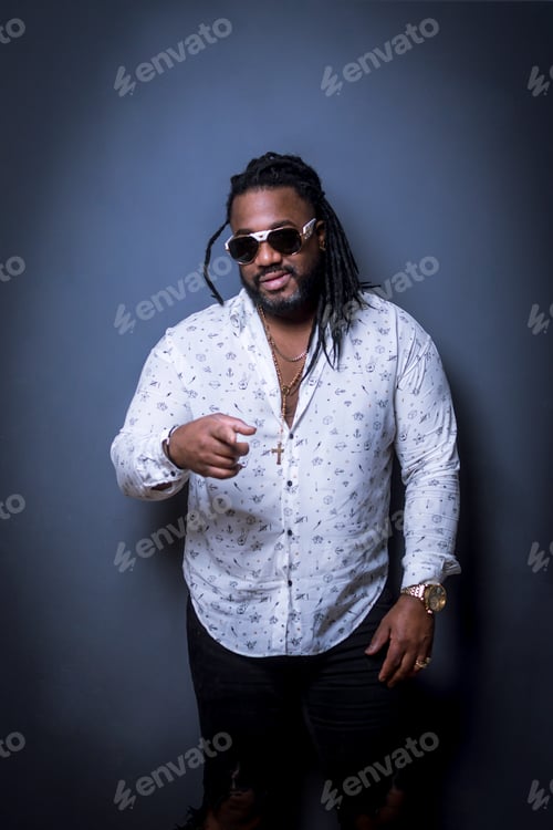 Preview: Man with dark skin and curly hair wearing jewelry and sunglasses.