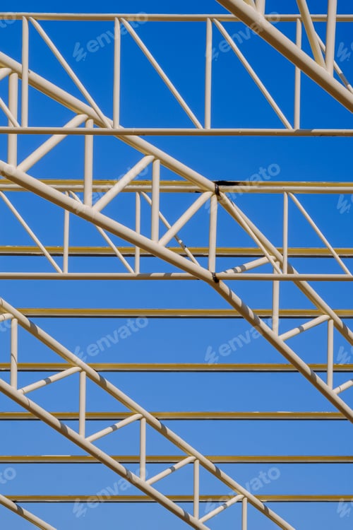 Preview: Metal building roof structure in construction area against blue sky background in vertical frame
