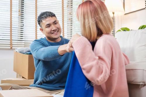 Preview: asian couple open cardboard boxes while moving to new home