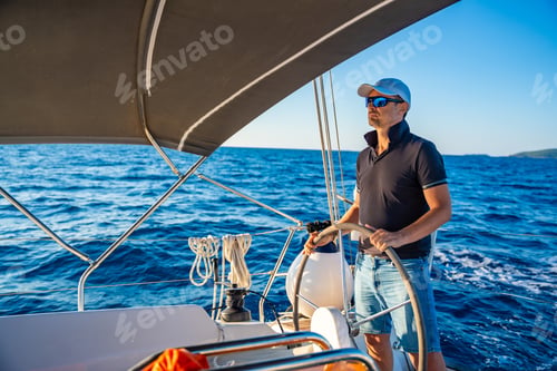 Preview: Young man captain stands at the helm and controls a sailboat during a journey by sea