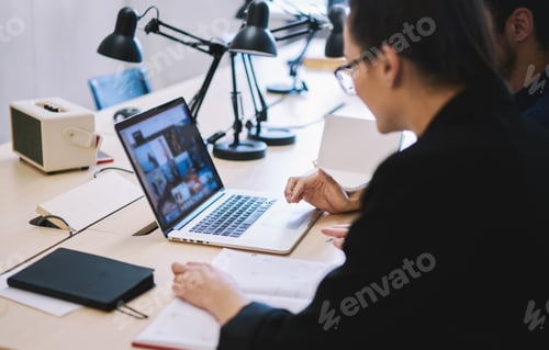 Preview: Colleagues preparing report using laptop in office
