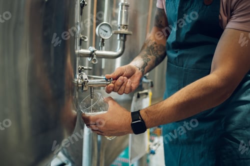 Preview: Close shot of a man filling glass of beer on a tap in brewery