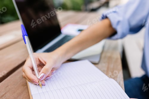 Preview: Closeup businesswoman hand holding pen writing on notebook outside
