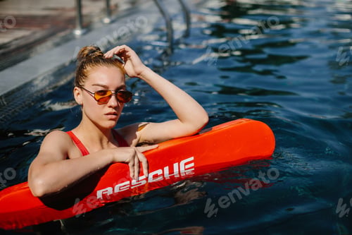 Preview: Lifeguard watching swimming pool with rescue tube