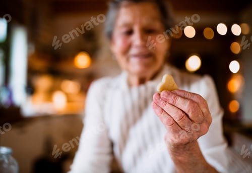 Preview: A close-up of elderly woman making cakes in a kitchen at home, holding a biscuit.