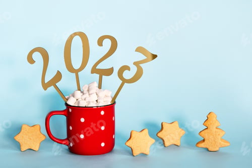 Preview: Christmas or New Year 2023 creative concept. Hot chocolate in red mug and golden numbers 2023