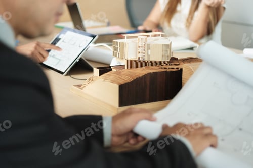 Preview: Miniature Building At Business Meeting With Architect Looking at Blueprints