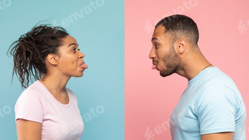 Preview: Funny black couple having fun and sticking tongue out at each other, standing over blue and pink