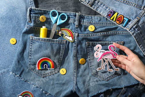 Preview: Denim clothing and decorative accessories in hand, top view