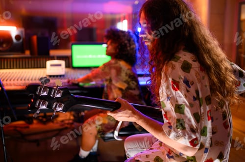 Preview: Rear view of a man guitarist playing while recording in a music studio