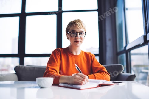 Preview: Calm woman taking notes while working alone