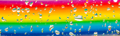 Preview: A rainbow behind a glass windows with water drops, Point of view, from behind the glass with drops.