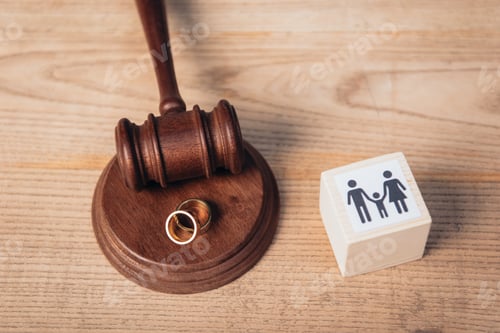 Preview: top view of golden rings on gavel near wooden cube with family, divorce concept