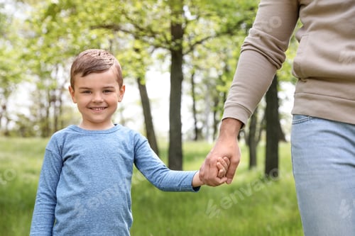 Preview: Happy little child holding hands with his father in park. Family time