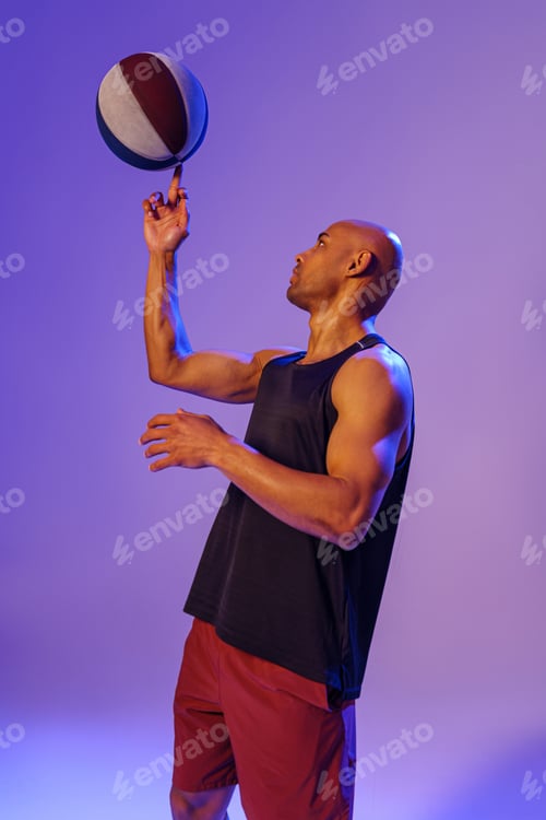 Preview: Professional basketball player spinning ball on his finger on studio background