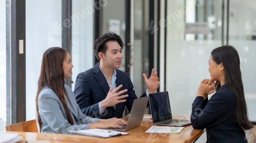 Preview: Three business professionals engaged in a meeting around a table