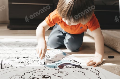 Preview: Cute little boy drawing with felt pens on floor at home. Early education concept.