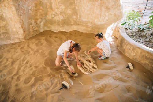 Preview: two girls have fun digging in the sand at adventure park, selective focus, sisters, friends