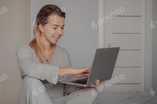 Preview: A young woman works on a laptop in the bedroom