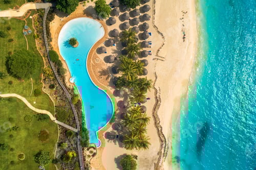 Preview: Aerial view of pool, umbrellas, sandy beach with green trees