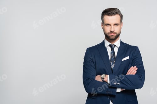 Preview: bearded businessman in blue blazer standing with crossed arms isolated on grey