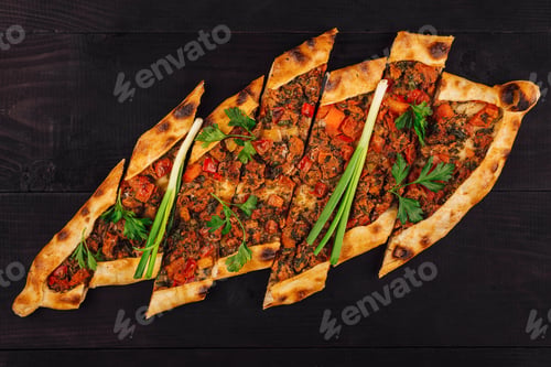 Preview: Turkish pide with meat and vegetables on black wooden table