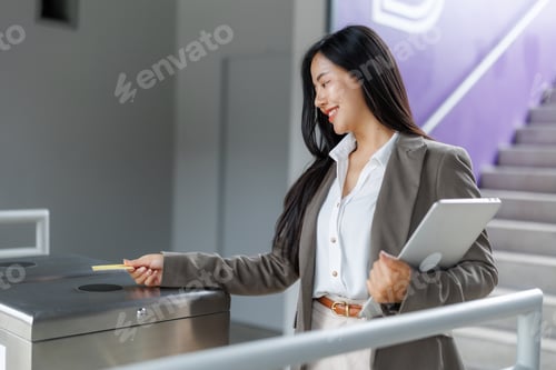Preview: Young manager using her badge to enter the office while holding laptop