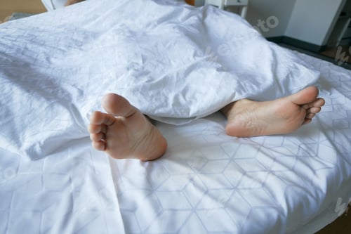 Preview: young Woman lying with bare feet in bed,