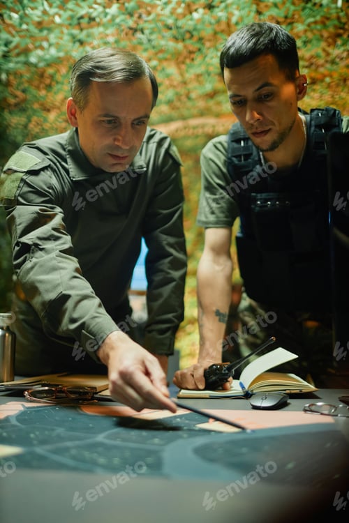 Preview: Young and mature officers in uniform looking at map during discussion