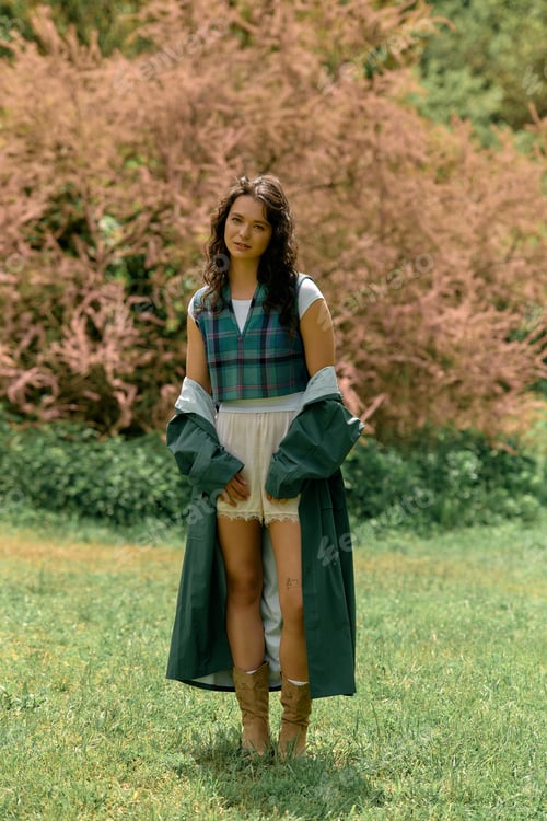 Preview: Stylish young woman in a trendy raincoat enjoying a summer day outdoors